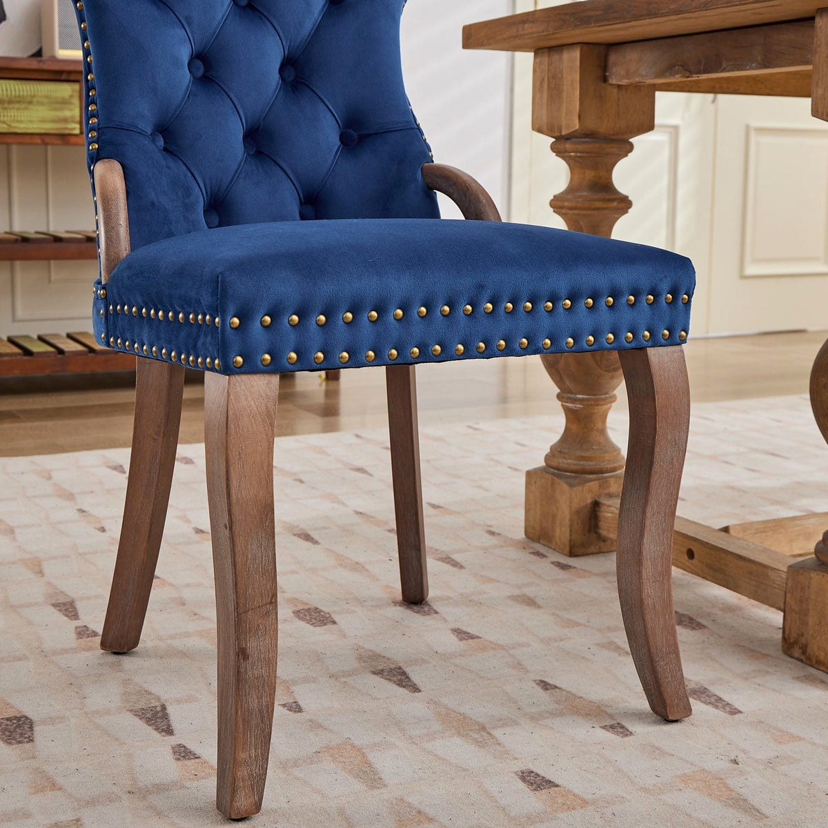 Blue velvet dining chair with a tufted back, wood handle, and curved wood legs