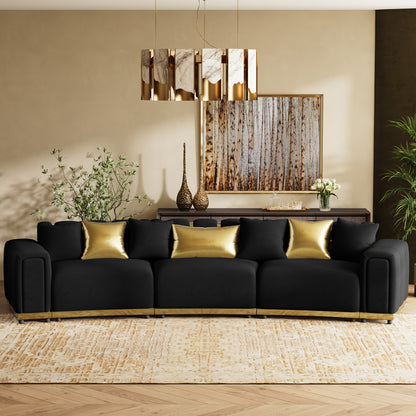 Curved Velvet Sofa with Metal Trim — black curved sofa with gold pillows in a living room.