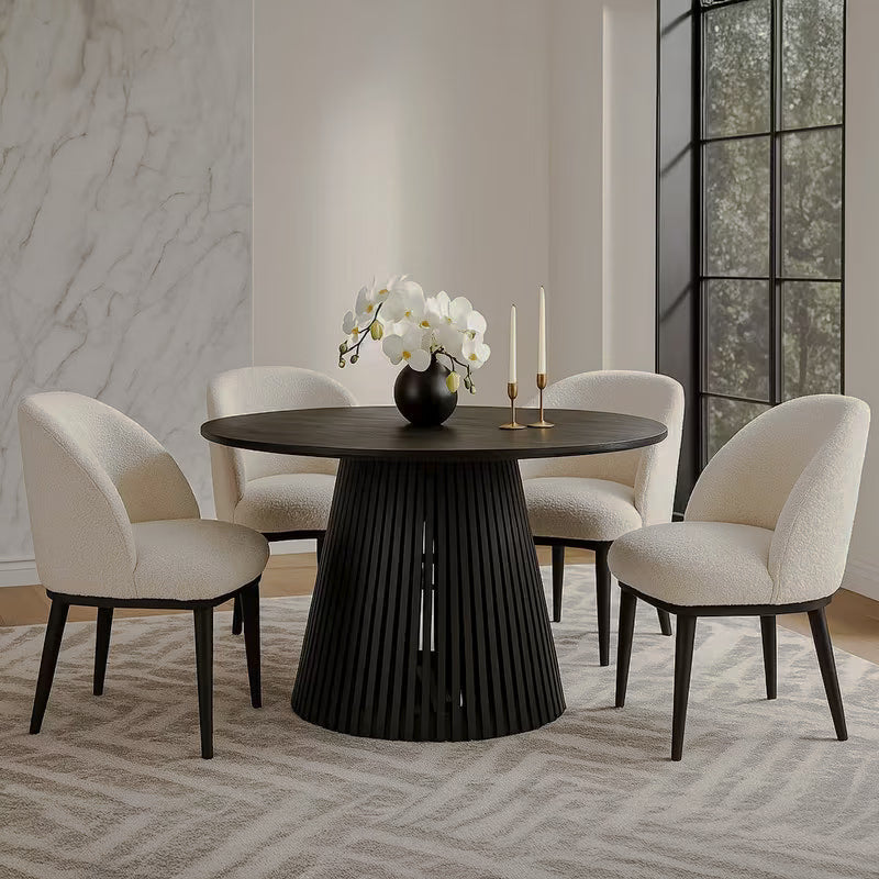 Round black dining table with cream chairs in a bright room