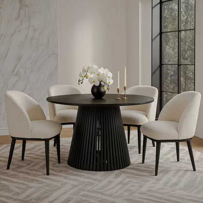 Round black dining table with cream chairs in a bright room