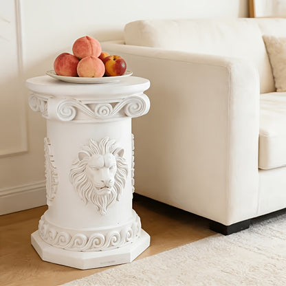 White lion-relief table beside a cream sofa with fruit on its round top.