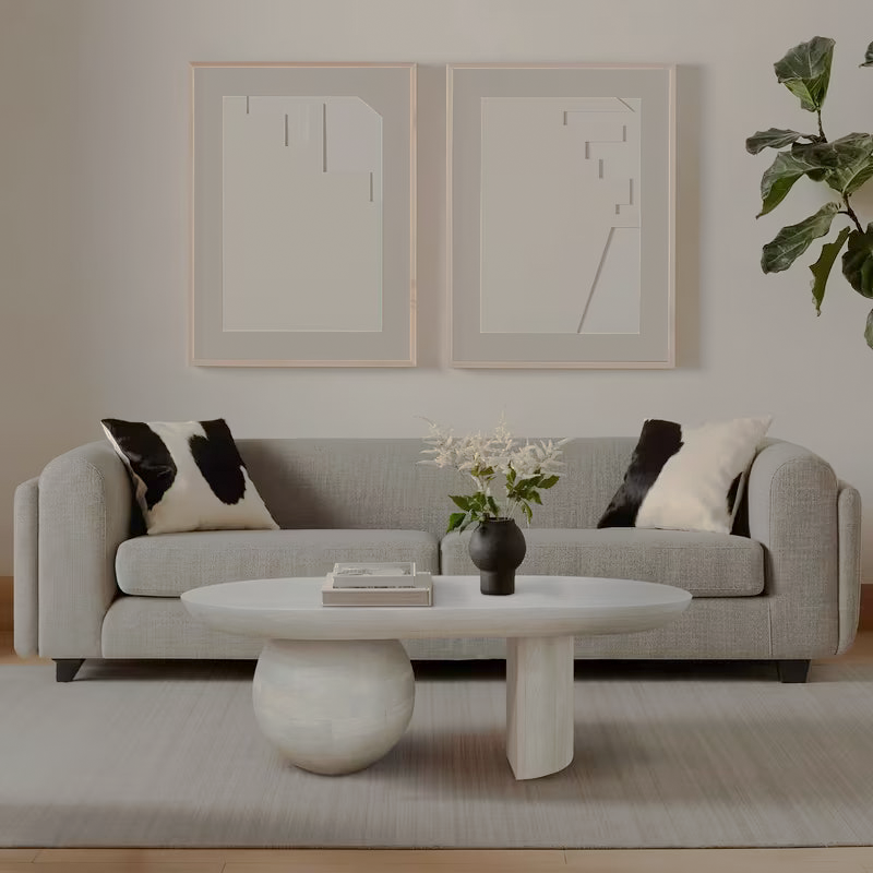 Whitewashed sculptural coffee table with rounded and slab supports in a living room