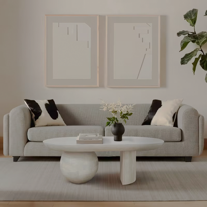 Whitewashed sculptural coffee table with rounded and slab supports in a living room