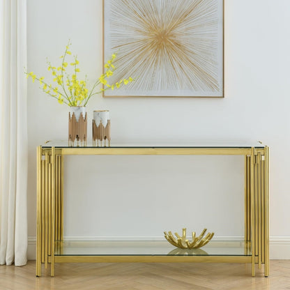 Clear glass and gold frame console with floral branches against a light wall.