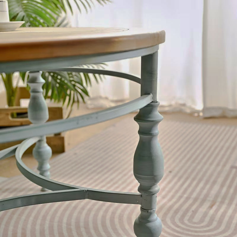 Close-up of pale blue turned table legs and curved stretchers beneath a natural wood-look top