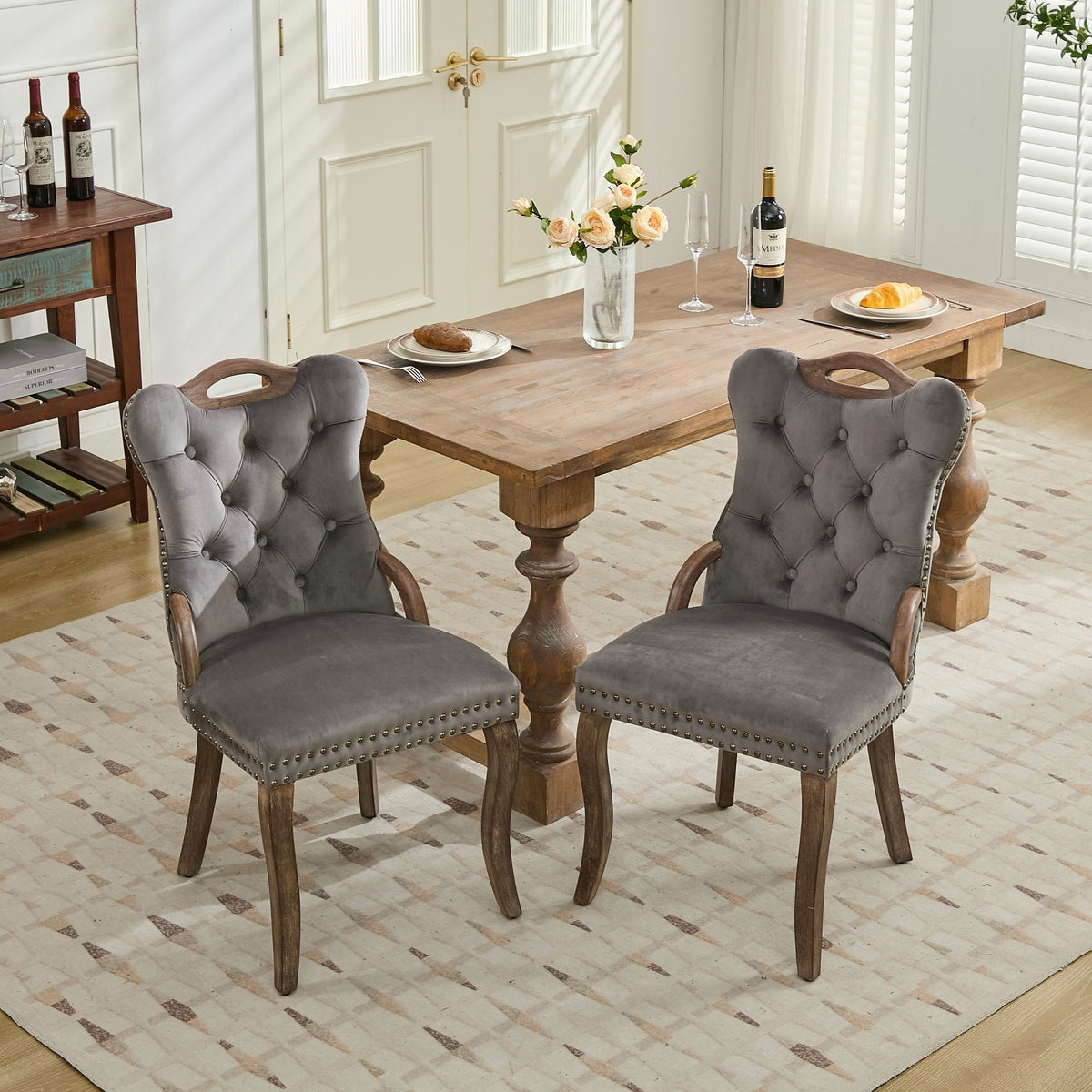 Gray velvet dining chair with a tufted back, wood handle, and curved wood legs