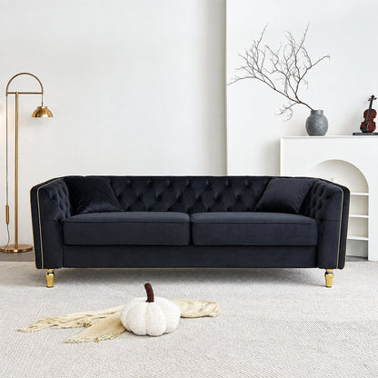 Black tufted sofa with gold-tone piping in a bright living room