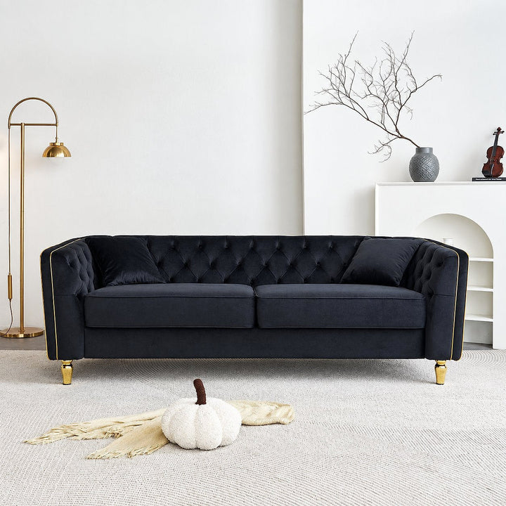 Black tufted sofa with gold-tone piping in a bright living room