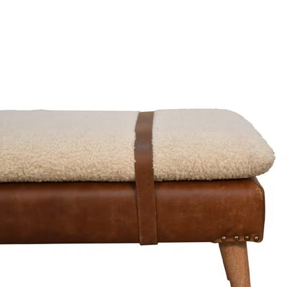Seat edge detail showing textured cream upholstery, a brown strap, and nailhead trim