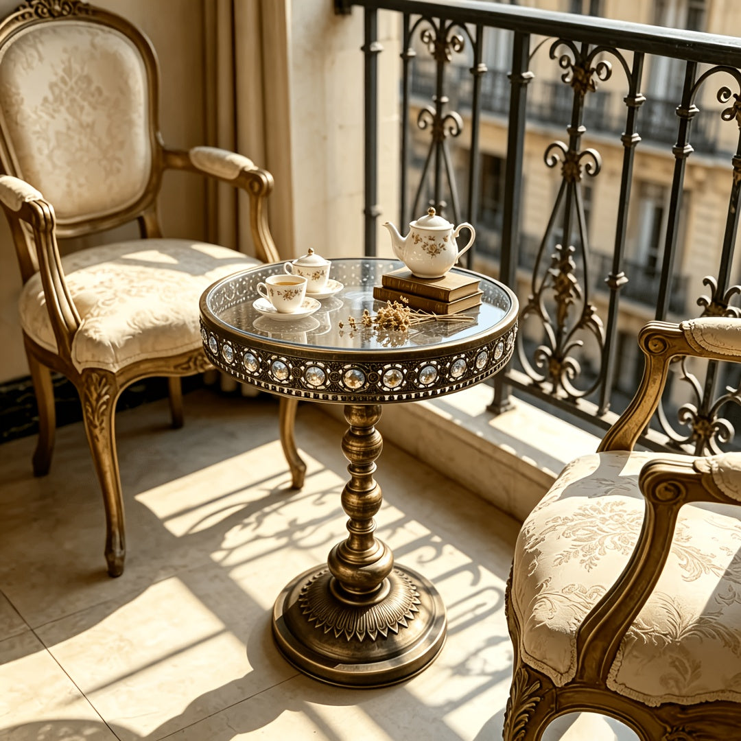 Bronze glass-top pedestal table with decorative inlays beside a classic chair.