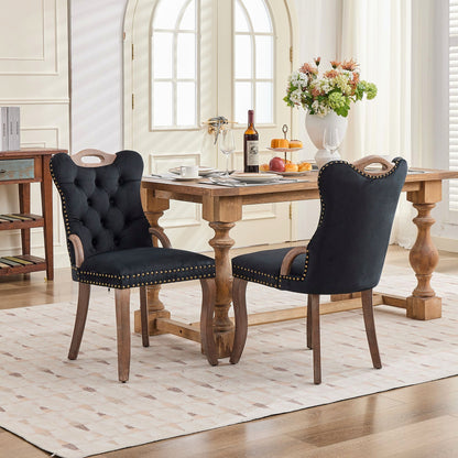Black velvet dining chair with a tufted back, wood handle, and curved wood legs