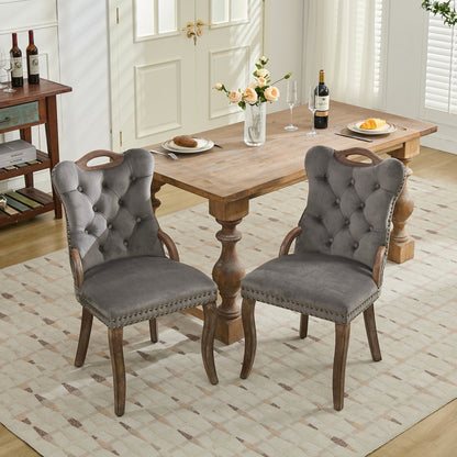Gray velvet dining chair with a tufted back, wood handle, and curved wood legs