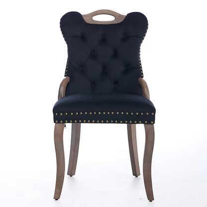Black velvet dining chair with a tufted back, wood handle, and curved wood legs