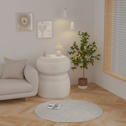 White folding side table with round white top beside a sofa