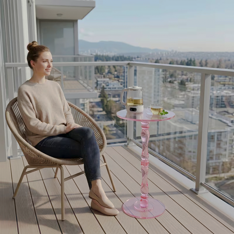 Pink acrylic pedestal table beside a chair on a balcony