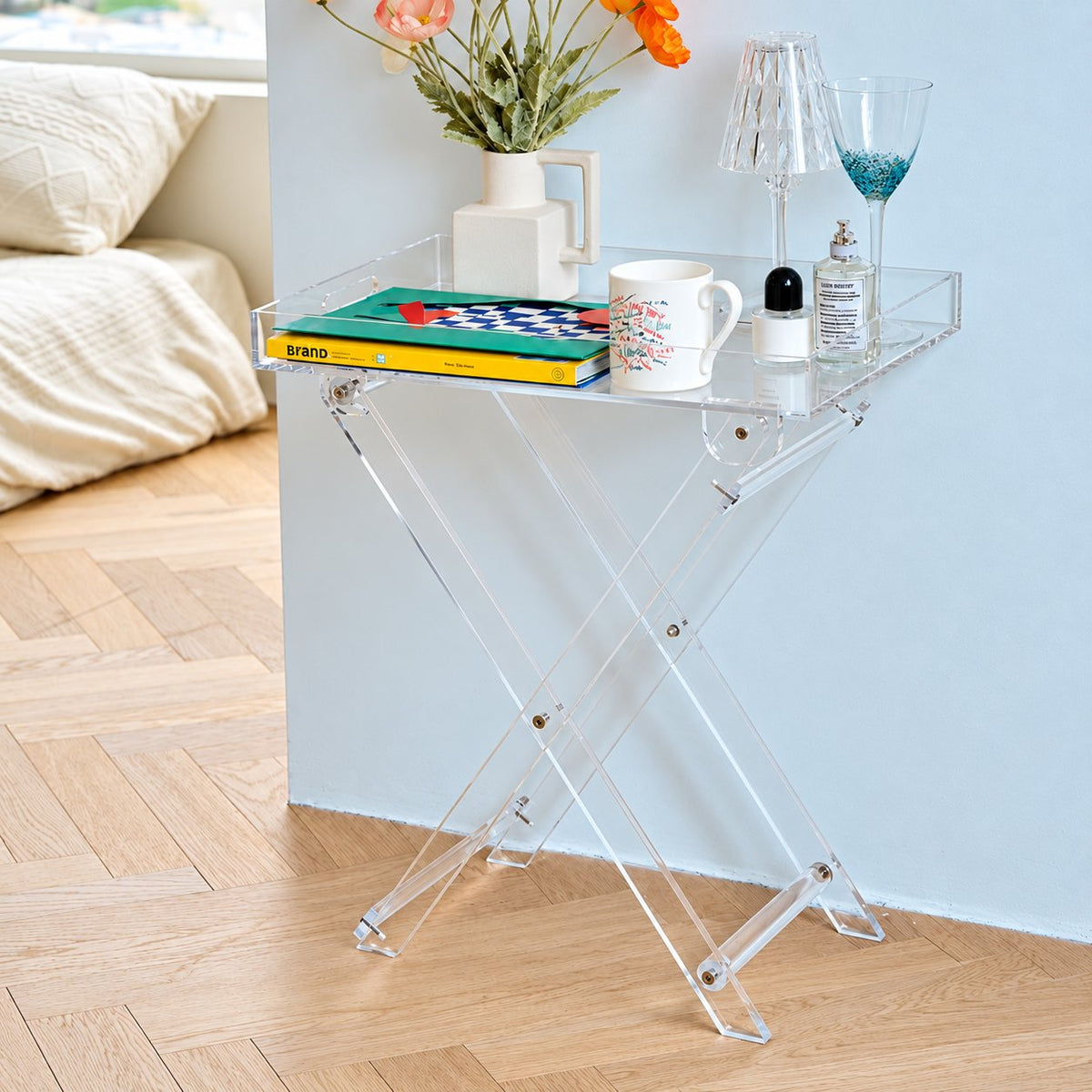 Luma Folding Tray Table — clear acrylic tray and crossed folding frame with books and flowers, full lifestyle view