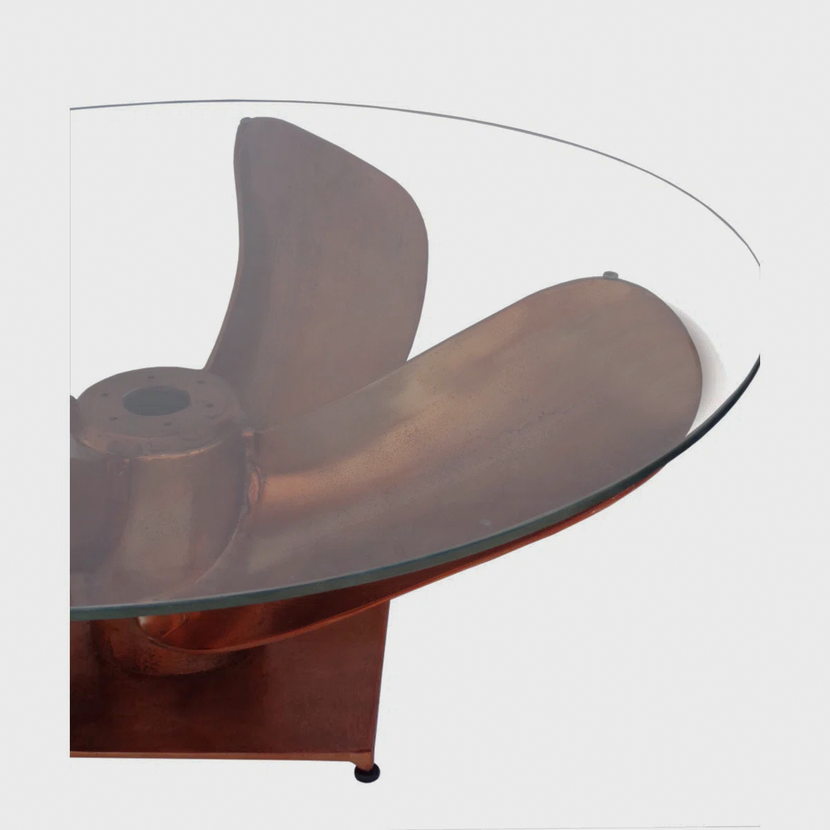 Close-up of the clear tabletop edge above a copper-tone sculptural support
