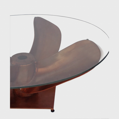 Close-up of the clear tabletop edge above a copper-tone sculptural support