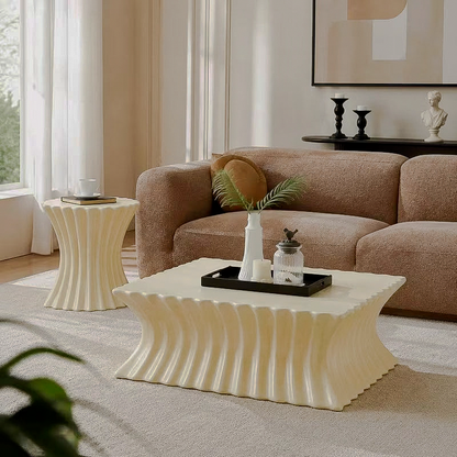 Cream fluted coffee table and matching hourglass-shaped side table beside a brown sofa