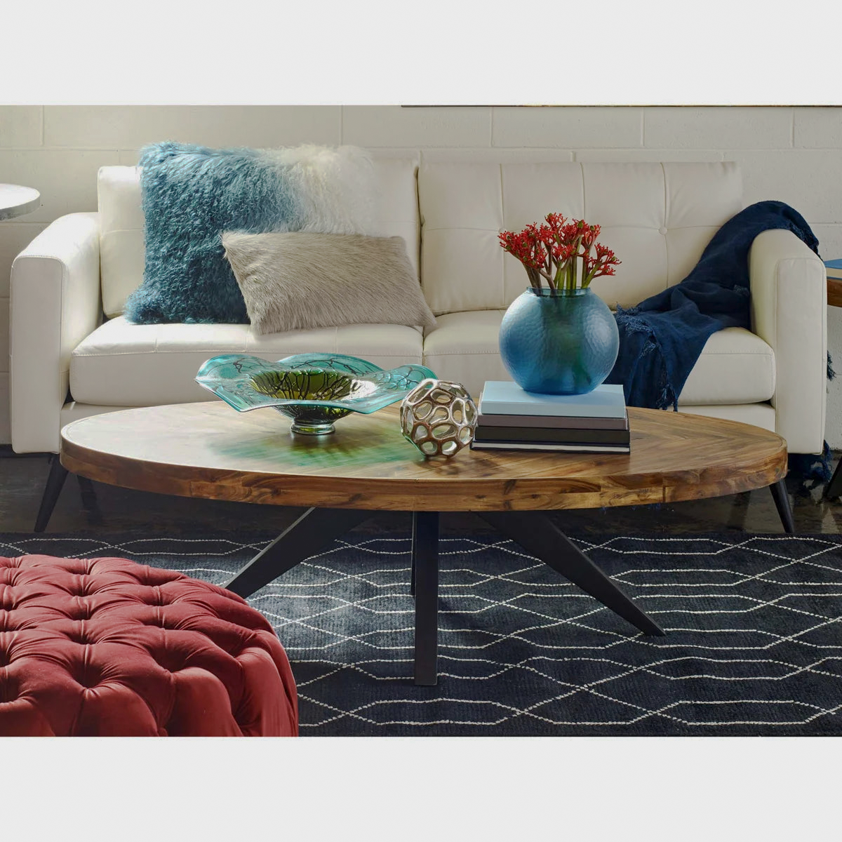 Oval patterned coffee table styled with blue glass vases beside a sofa