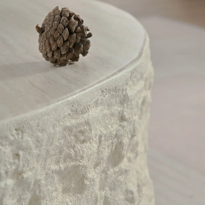 Close-up of the pale tabletop edge and rough cream stone-look side of a round table