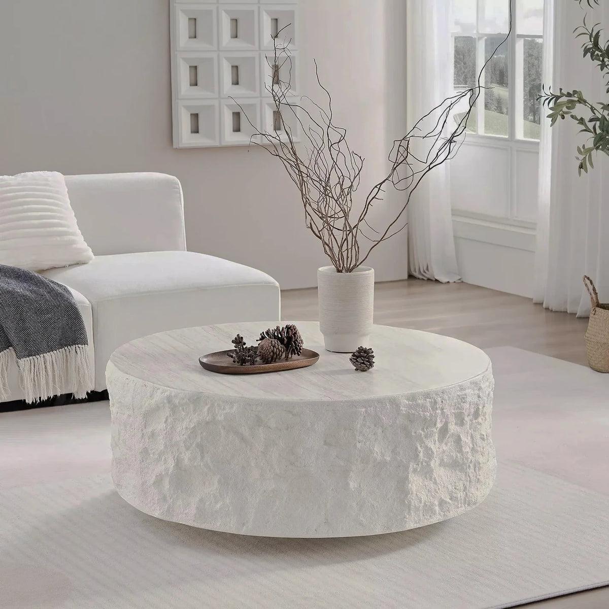 Low round cream table with a pale stone-patterned top and rough textured sides in a bright room