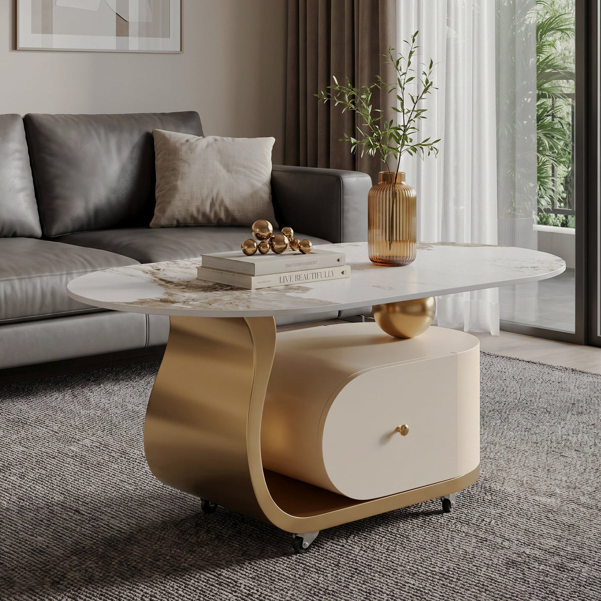 Oval cream and gold-tone coffee table with a stone-patterned top, front drawer and caster wheels beside a gray sofa
