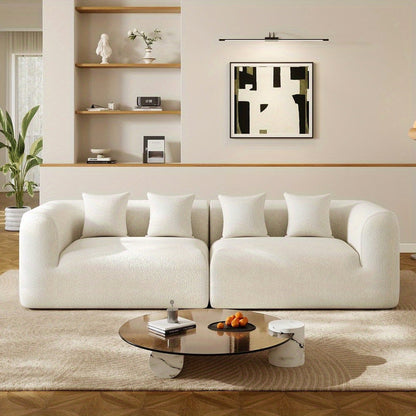 Front view of the light neutral modular sofa with four matching pillows in a styled living room.