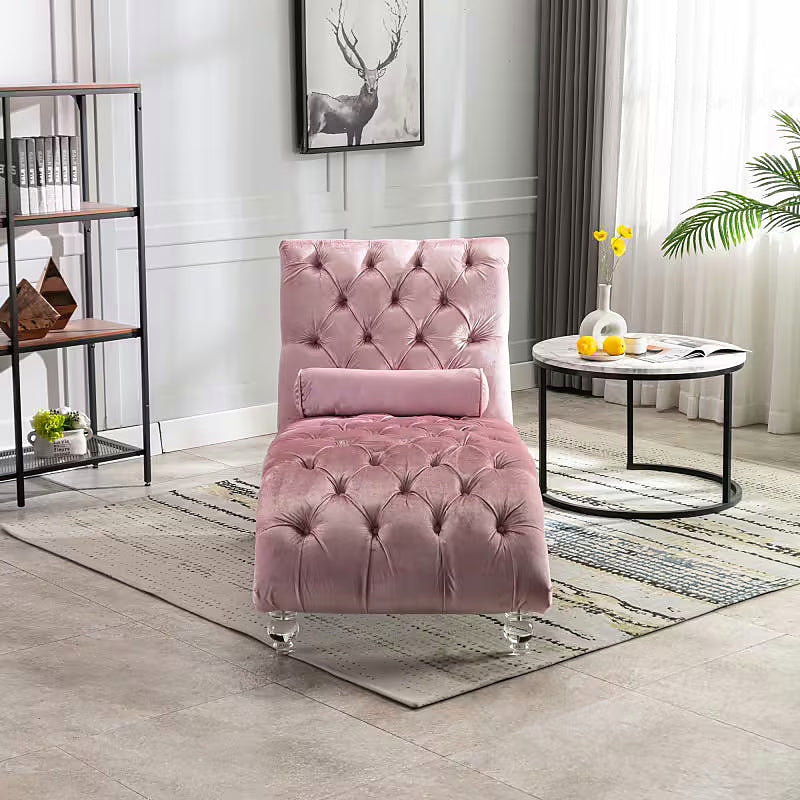 Pink velvet tufted chaise lounge with clear acrylic feet and a bolster pillow