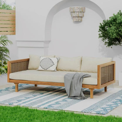Patio sofa with beige cushions and woven side panels in a courtyard