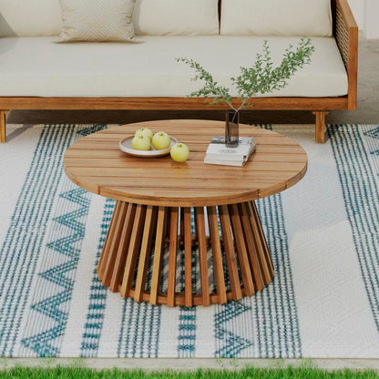 Round slatted-top patio table with a flared slatted base in front of a sofa
