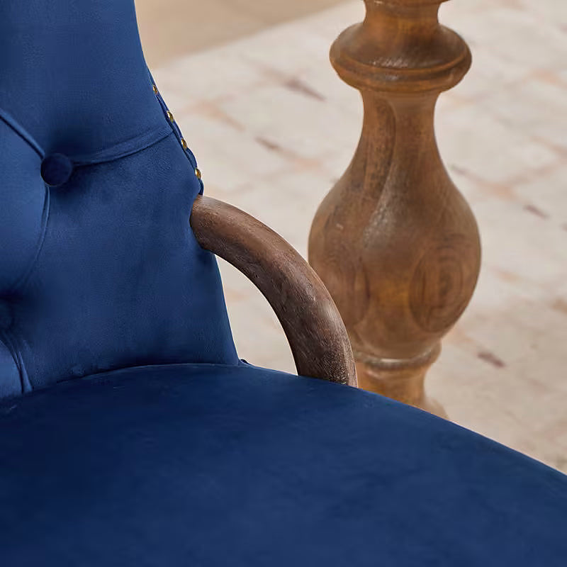 Blue velvet dining chair with a tufted back, wood handle, and curved wood legs