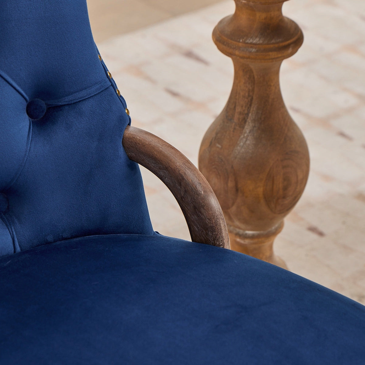 Blue velvet dining chair with a tufted back, wood handle, and curved wood legs