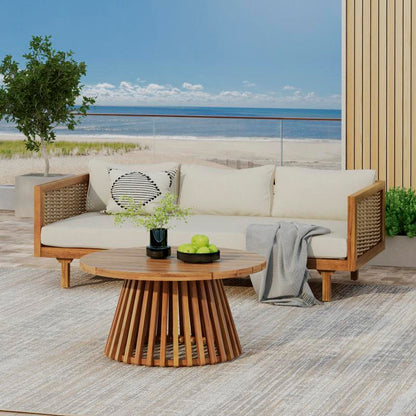 Angled view of a patio sofa with beige cushions and round slatted-base table