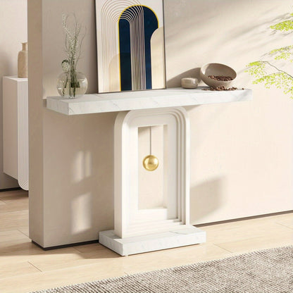 White console with gold sphere displayed against a pale wall in a sunlit hallway
