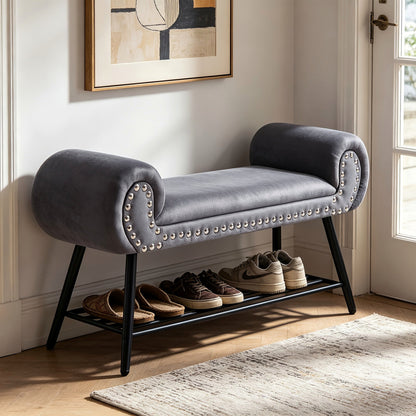 Gray rolled arm upholstered shoe bench with a black metal rack and silver tone nailheads