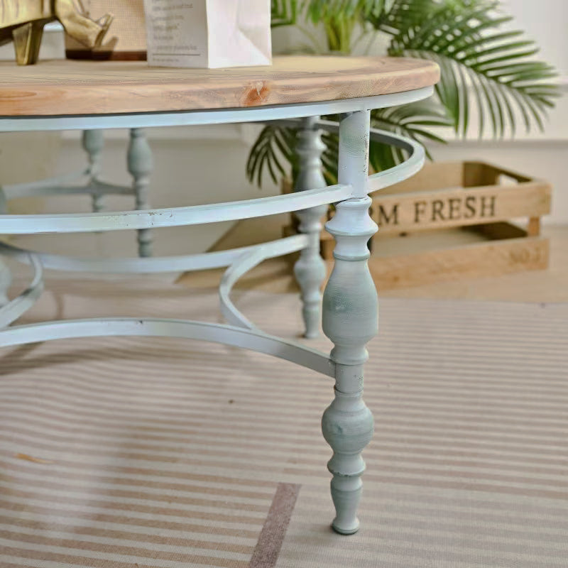 Pale blue turned leg and curved stretchers below a round wood-look table