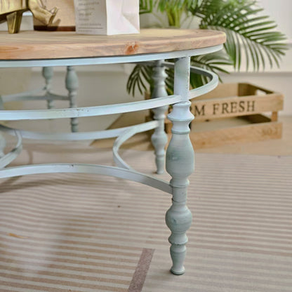 Pale blue turned leg and curved stretchers below a round wood-look table