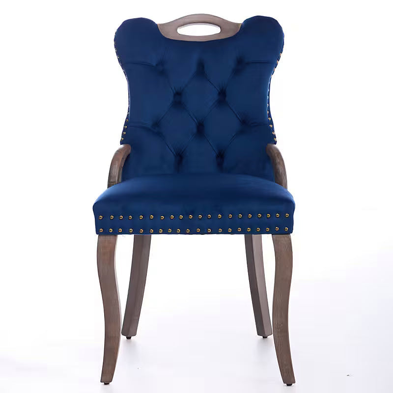 Blue velvet dining chair with a tufted back, wood handle, and curved wood legs