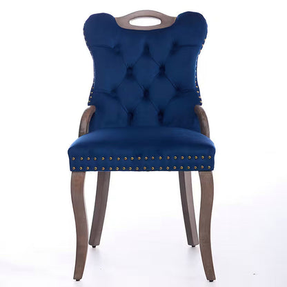 Blue velvet dining chair with a tufted back, wood handle, and curved wood legs