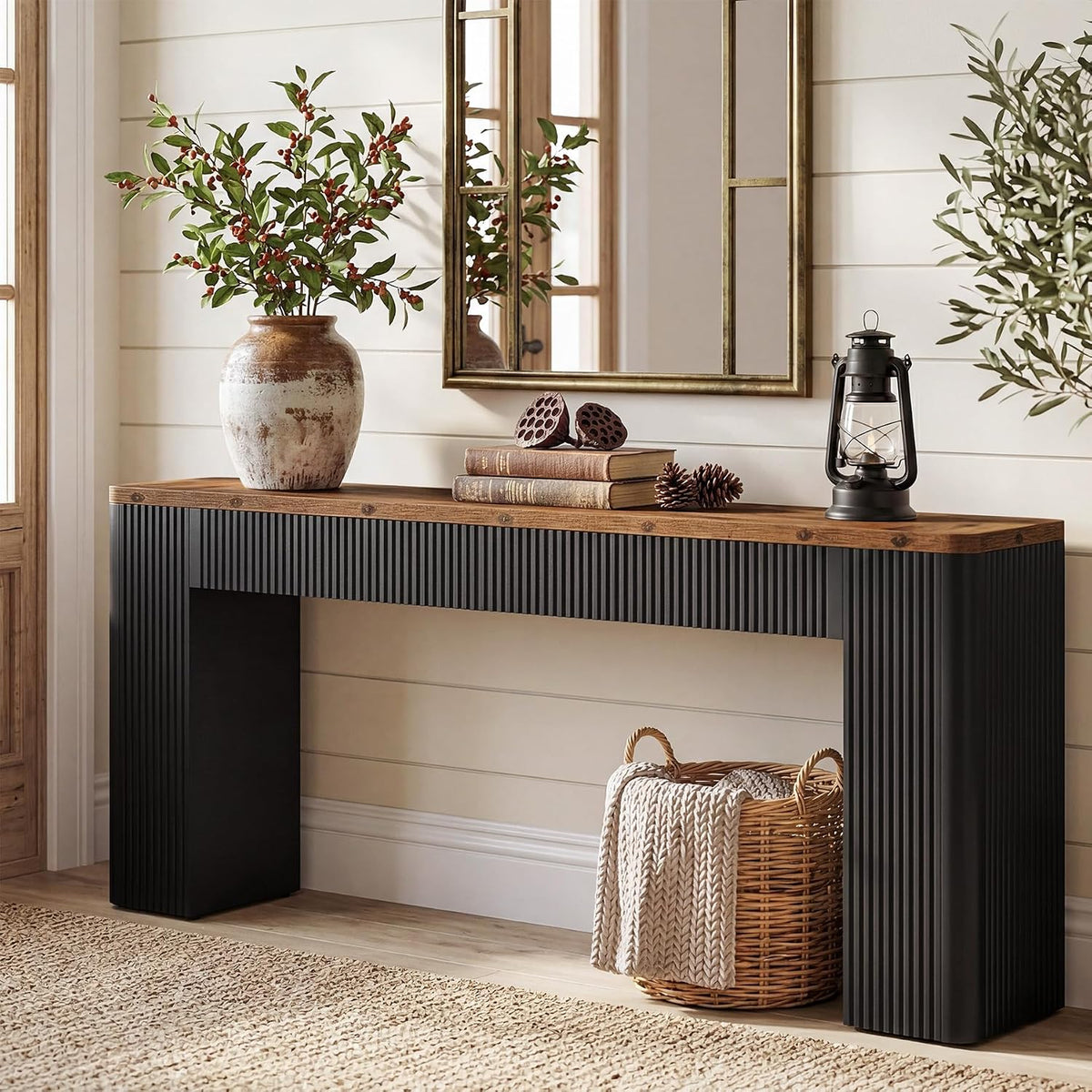 Extra-long console with brown top and black fluted sides styled below a mirror.