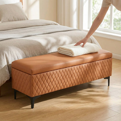 Brown diamond-quilted bench with dark legs at the foot of a bed