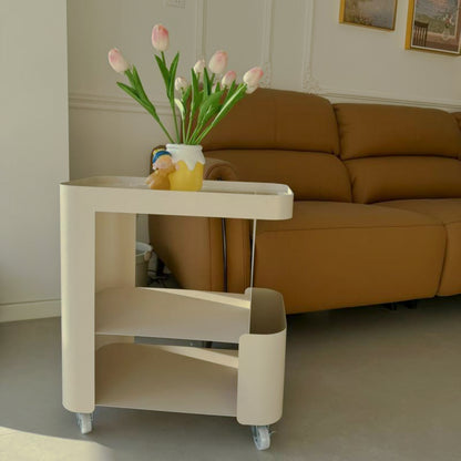 Angled view of rounded cream metal side table and side pocket