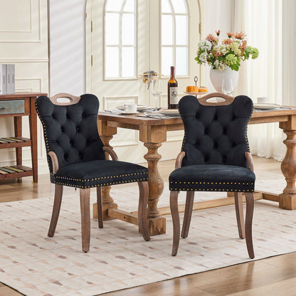 Black velvet dining chair with a tufted back, wood handle, and curved wood legs