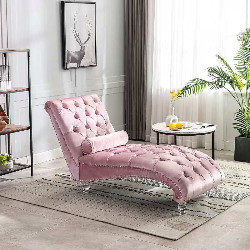 Pink velvet tufted chaise lounge with clear acrylic feet and a bolster pillow