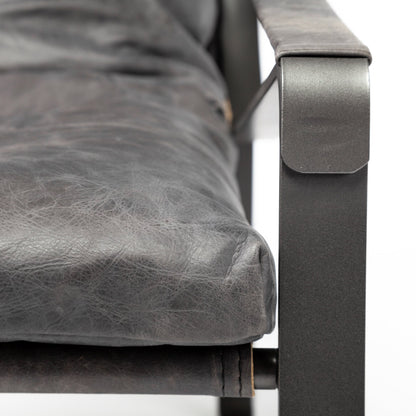 Close-up of the black leather upholstery, leather-wrapped arm and metal frame.
