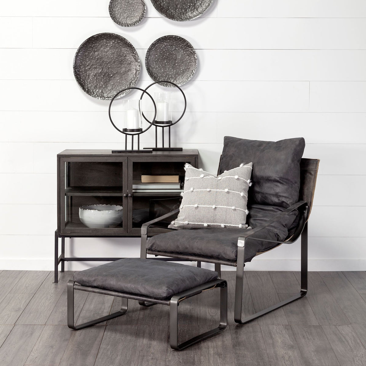 Black leather accent chair in a styled room; ottoman, cushion and accessories shown for styling and are not included.