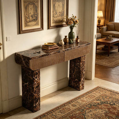 Dark marble-look console with natural-tone fluted drawers in a traditional entryway.