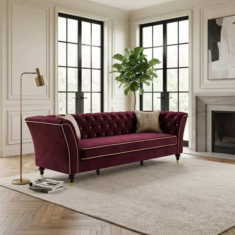 Chesterfield Sofa with Contrast Piping — burgundy sofa beside a fireplace.