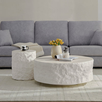 Two cream round tables with textured stone-look sides in front of a gray sofa